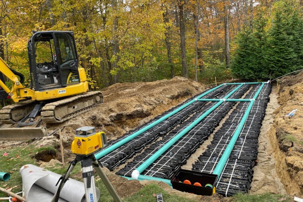 Large septic leach field with chambers and distribution piping being set to laser grade in autumn